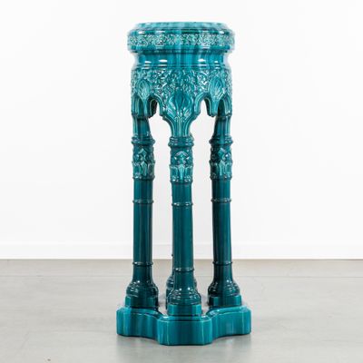 une table bleue posée sur un sol en béton, près d'un mur blanc