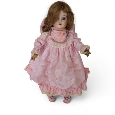 une poupée à l'ancienne, avec une robe rose et des chaussures roses