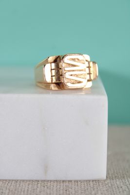 La bague-sceau en or repose sur un bloc de marbre blanc
