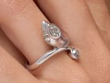 la main d'une femme tenant une bague en argent ornée d'une fleur