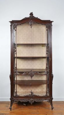 an antique wooden bookcase with wicker shelves on top of a hard wood floor