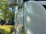 un camion blanc garé dans un champ, avec des arbres en arrière-plan