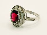 a close up of a ring with a red stone surrounded by diamonds