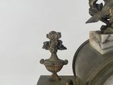a clock sitting on a table next to a vase
