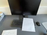 a desk with a computer monitor, keyboard, mouse and other items on it