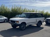 a white land rover parked in a parking lot next to other cars