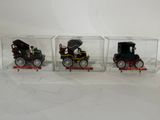 three small toy cars are in a clear box on a white surface