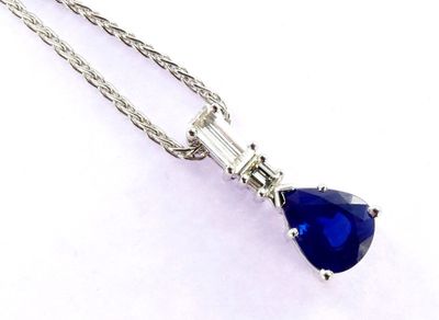 a close up of a necklace with a blue tear shaped stone
