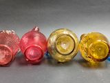 four different colored glass cups are lined up in a row