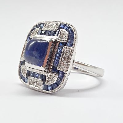un gros plan d'une bague ornée d'une pierre bleue entourée de saphirs bleus