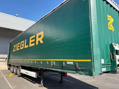 un semi-remorque vert garé devant un immeuble