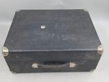 an old black suitcase sitting on a white surface