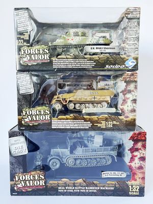 trois boîtes de véhicules militaires miniatures exposées sur une table