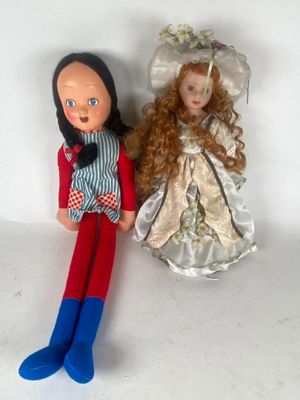 two dolls sitting next to each other on a white surface
