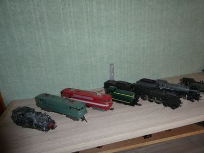 several toy trains are lined up on a table in front of a green wall