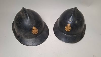pair of black helmets with gold emblems on them sitting on a white surface