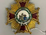 une image représentant un insigne doré et rouge sur lequel figure l'image d'un homme dans un bateau