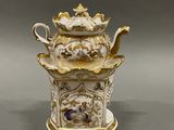 a white and gold teapot with a lid on a table