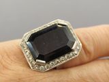a person holding a ring with a black stone on it