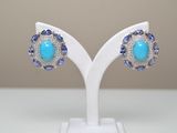 une paire de boucles d'oreilles ornées de pierres bleues sur un support blanc