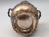 a silver vase sitting on a table with a chain around it