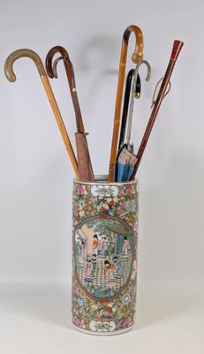 un vase posé sur une table, contenant des parapluies et des stylos