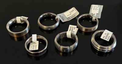 six types différents de bagues, accompagnées d'étiquettes, posées sur une table