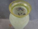 a green vase with a yellow rim sitting on a table