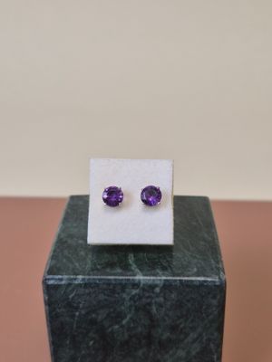 une paire de boucles d'oreilles en améthorate posées sur un bloc de marbre
