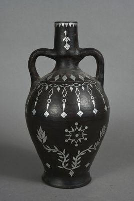 a black vase with white designs on it on a gray background