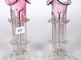 une paire de vases en verre rose posés sur une table blanche