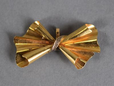 a gold bow brooch with a diamond in it