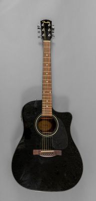 une image représentant une guitare acoustique noire posée sur un mur blanc