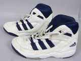 une paire de baskets Adidas blanches et bleues posées sur une surface blanche