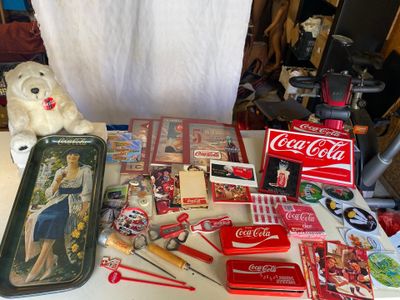une table sur laquelle sont disposés des objets liés au Coca-Cola et un ours en peluche