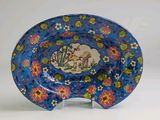 une assiette bleue sur laquelle sont représentés un cheval et des fleurs