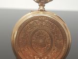 a gold pocket watch sitting on a black surface