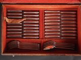 many forks and spoons in a box with a leaf
