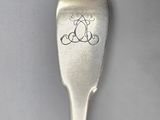 silver spoon with a monogram on it sitting on a white surface