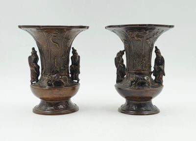 paire de vases en bronze ornés de figures sur fond blanc