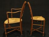 pair of antique wooden chairs with cane backrests on black background