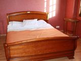 a wooden bed in a room with a red wall