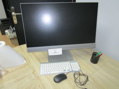 un écran d'ordinateur et un clavier posés sur un bureau, avec une lampe