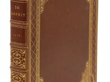un vieux livre à la couverture brune posé sur une surface blanche