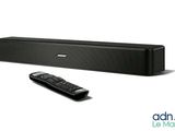 the sound bar is black and has a remote in front of it