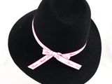 black hat with pink ribbon and bow on white background