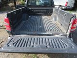 a truck that is sitting in the dirt with its bed open