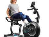 La femme est assise sur un vélo d'appartement, les jambes croisées.