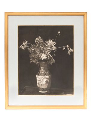 photographie en noir et blanc d'un vase contenant des fleurs, posé sur une table