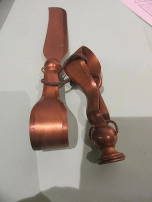 a small copper object on a table next to a piece of paper